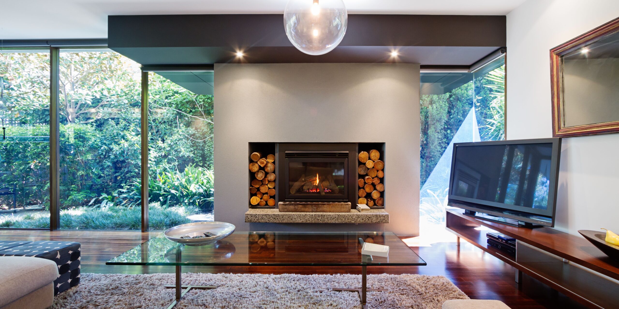 Modern living room with large windows showcasing lush greenery.